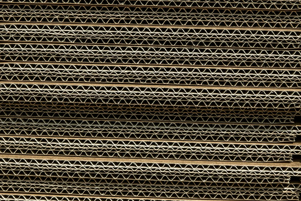 Stacked corrugated board seen edge on, the fluting visible through the stack